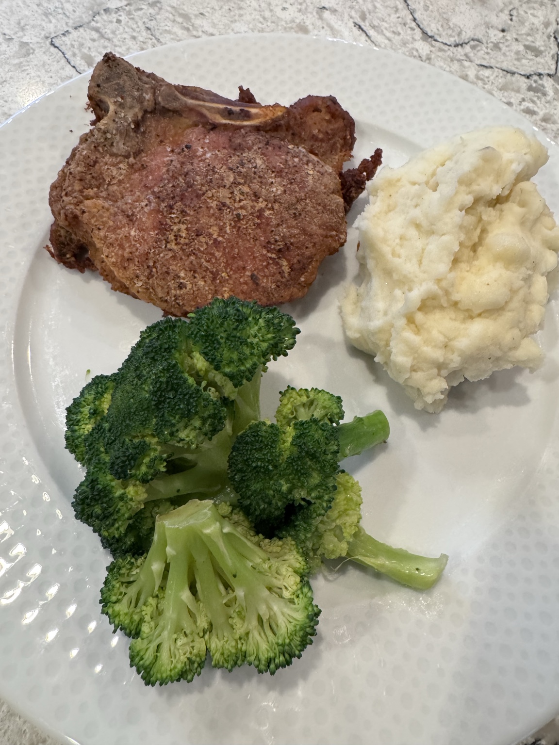 A simple pork chop dinner with mashed potatoes and broccoli